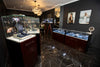 Jewelry display cases in a high-end store with chandeliers and framed pictures on the wall.